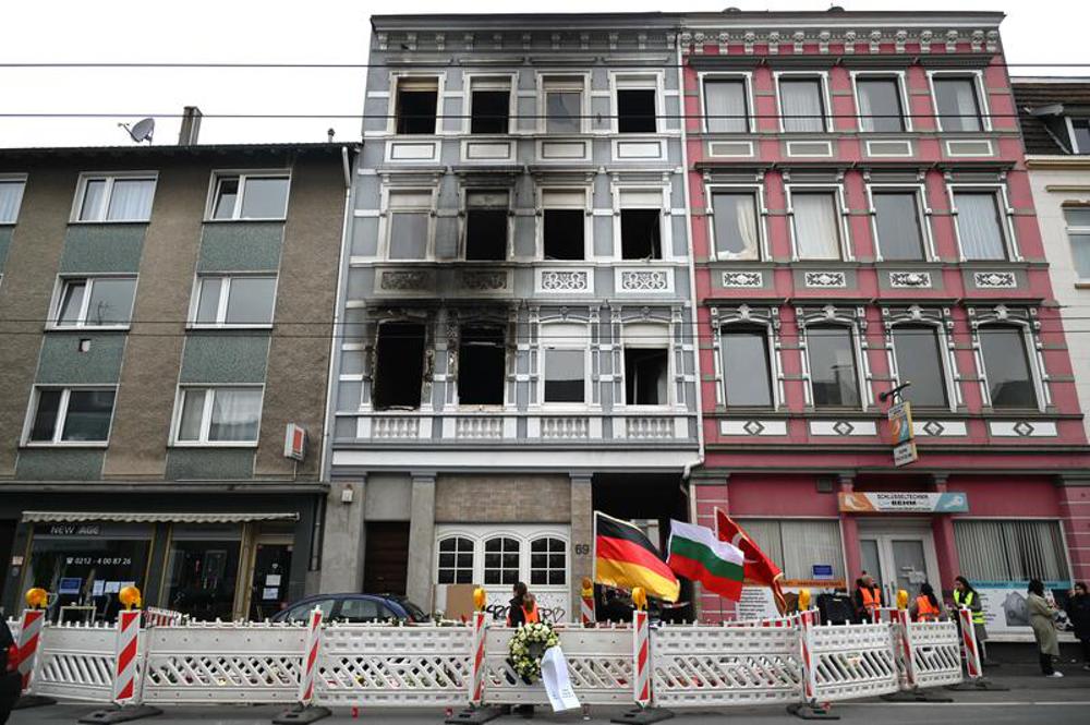 Fahnen und Absperrungen vor dem ausgebrannten Mehrfamilienhaus in Solingen