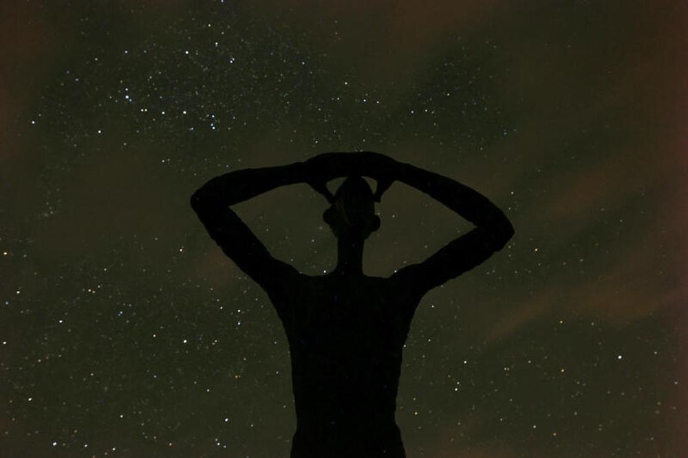 Bronzefigur "Der Utkieker" vor dem Sternenhimmel auf Spiekeroog