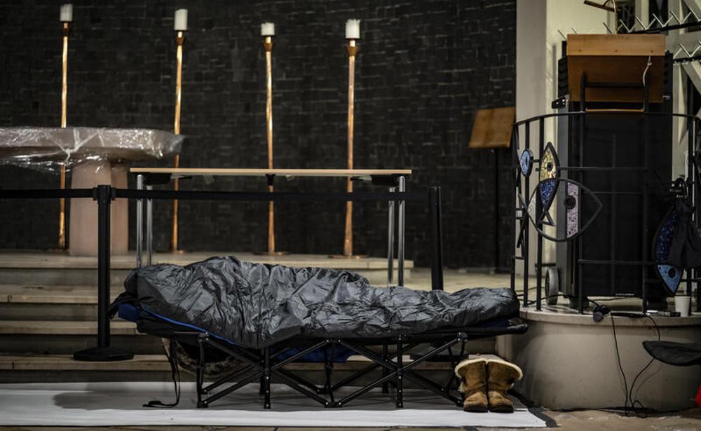 Ein Mann in seinem Schlafsack auf einem Feldbett in der Weißfrauen-Diakoniekirche.