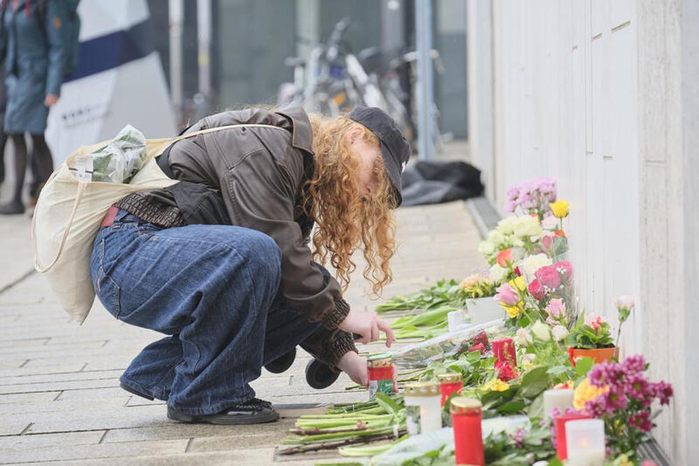 Eine trauernde Frau legt Blumen und Kerzen vor dem Paulinum am Augustusplatz in der N&auml;he des Tatorts nieder.