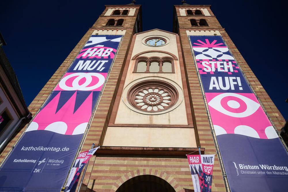Banner mit dem Leitmotiv "Hab Mut, steh auf!" zum Katholikentag h&auml;ngen an der Fassade des Kiliansdoms in der Innenstadt in W&uuml;rzburg.